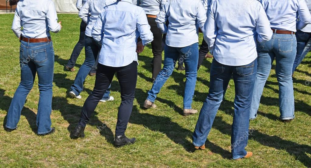 Line-Dance-Gruppe tanzt in Westernkleidung auf einem Holzboden
